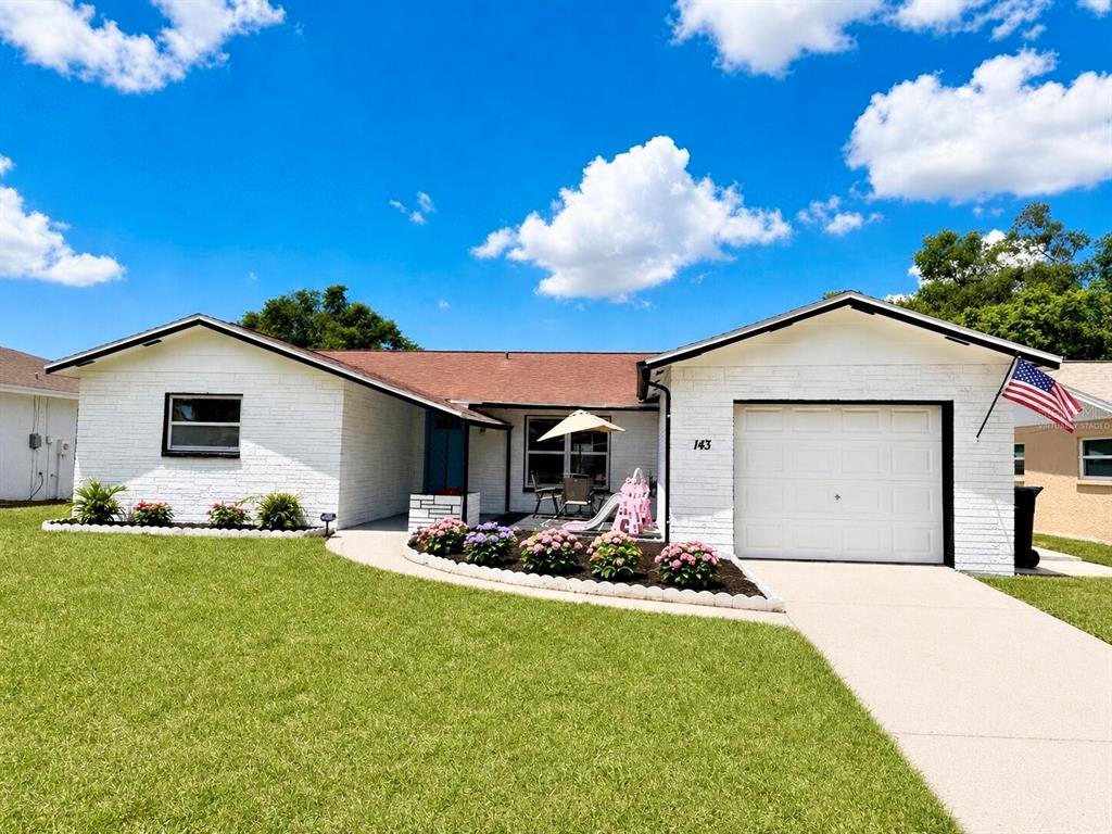 A white brick, single-story house with a garage and a front lawn under a blue sky — 143 VALLEY CIRCLE, BRANDON, FL
