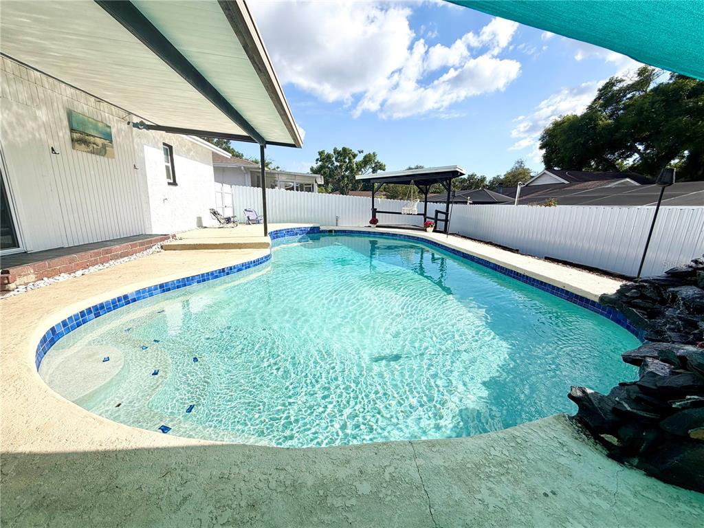 A backyard swimming pool with a rock feature, patio, and covered seating area — 143 VALLEY CIRCLE, BRANDON, FL