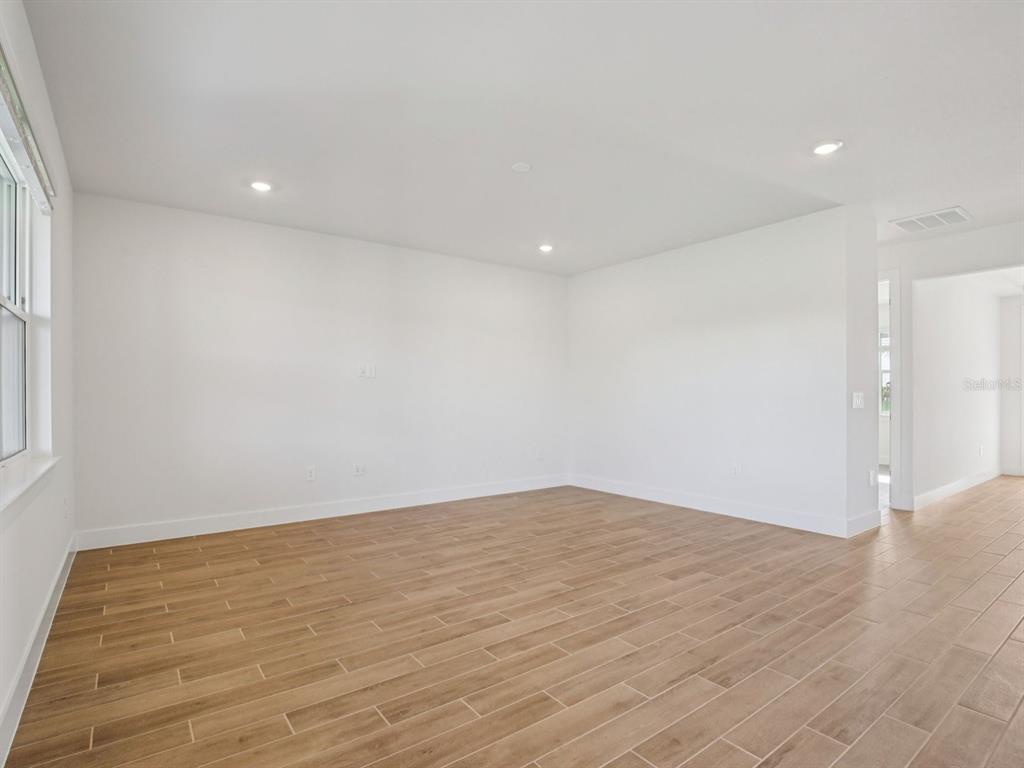 An empty room with white walls, recessed lighting, and light brown wood-look tile flooring — 156 SHADY EDGE LOOP, NOKOMIS, FL