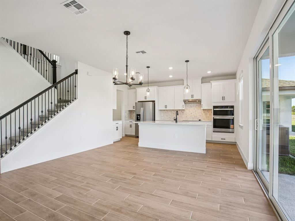 A modern kitchen with white cabinetry and an island overlooks an open living area — 156 SHADY EDGE LOOP, NOKOMIS, FL