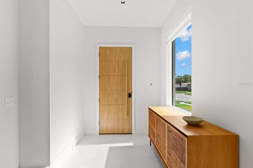 A bright entryway features a light wood door, white tile floors, and a wooden console — 5150 DARTMOUTH AVENUE N, ST PETERSBURG, FL