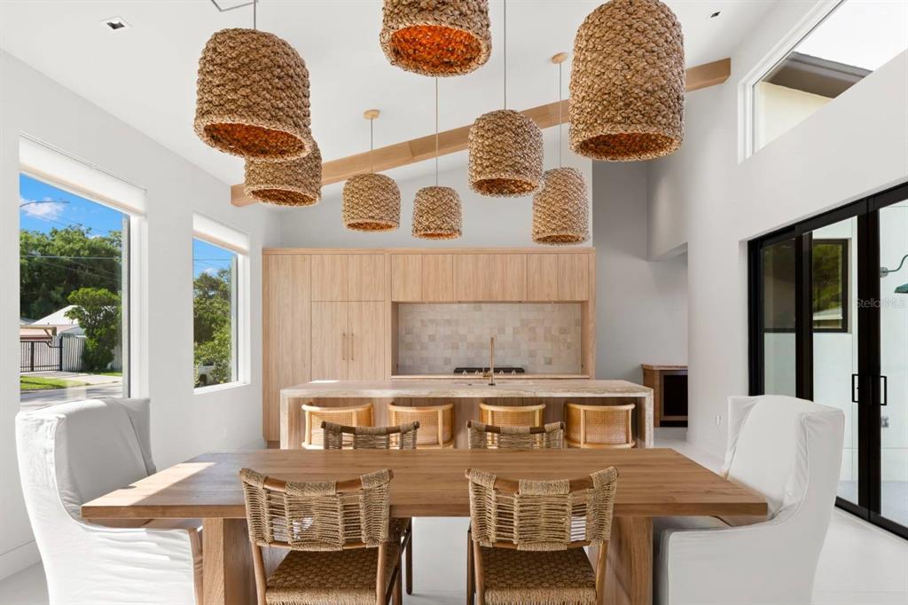 A modern kitchen and dining area features light wood cabinetry, woven pendant lights, and chairs — 5150 DARTMOUTH AVENUE N, ST PETERSBURG, FL