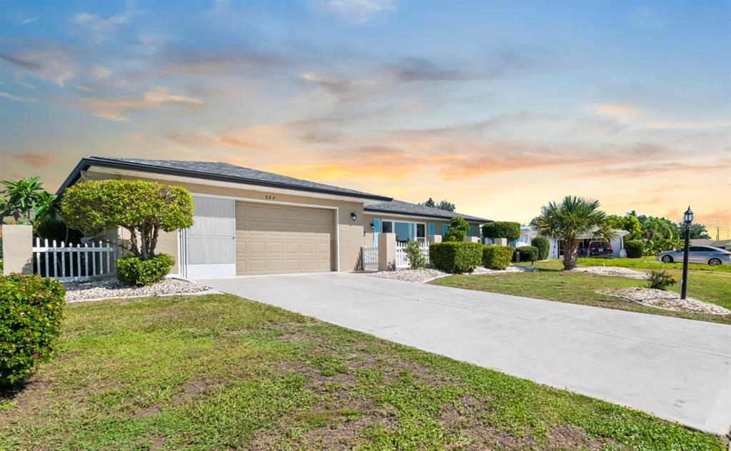 A single-story house with a tan exterior, a two-car garage, and a concrete driveway — 234 AMESBURY CIRCLE, SUN CITY CENTER, FL