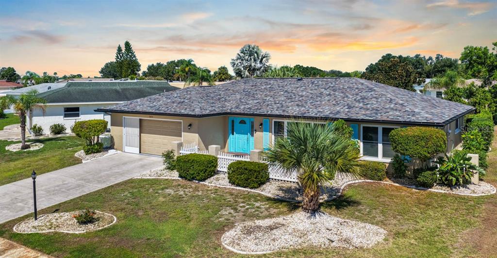 A single-story house with a tan exterior, a gray shingled roof, and a bright blue door — 234 AMESBURY CIRCLE, SUN CITY CENTER, FL