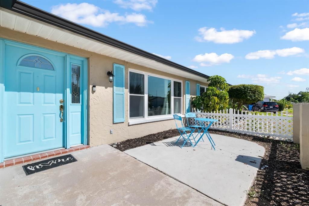 A light blue front door and matching shutters accent the exterior of a tan house — 234 AMESBURY CIRCLE, SUN CITY CENTER, FL