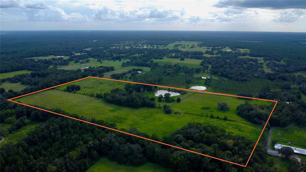 An aerial view shows a large, rectangular grassy field outlined in orange with a pond — NW 110TH AVENUE, REDDICK, FL