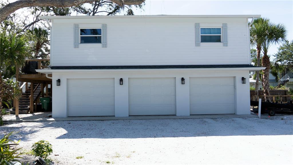 A two-story white house features a three-car garage on the ground level — 7233 MIDNIGHT PASS ROAD, SARASOTA, FL