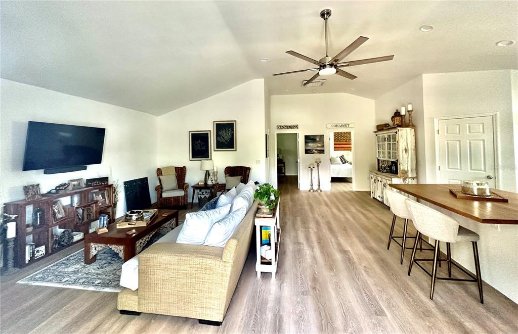 An open-concept living room and kitchen area features light wood flooring and a vaulted ceiling — 7233 MIDNIGHT PASS ROAD, SARASOTA, FL
