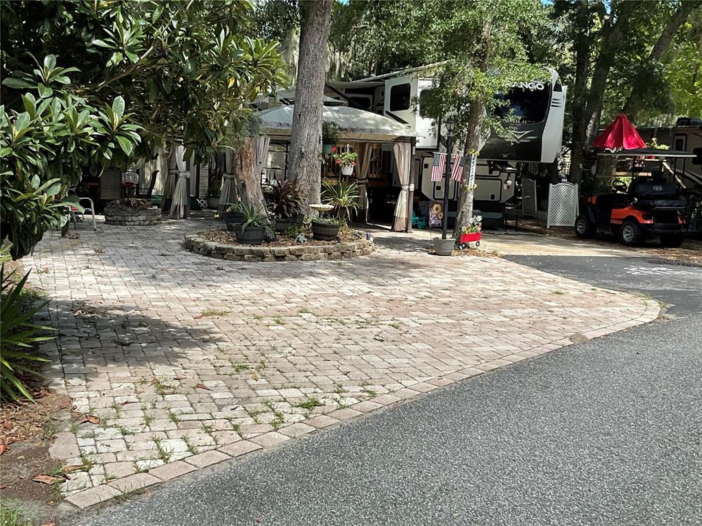 A paved driveway leads to a recreational vehicle parked under trees with a gazebo — 25191 NE 142ND PLACE, FORT MC COY, FL