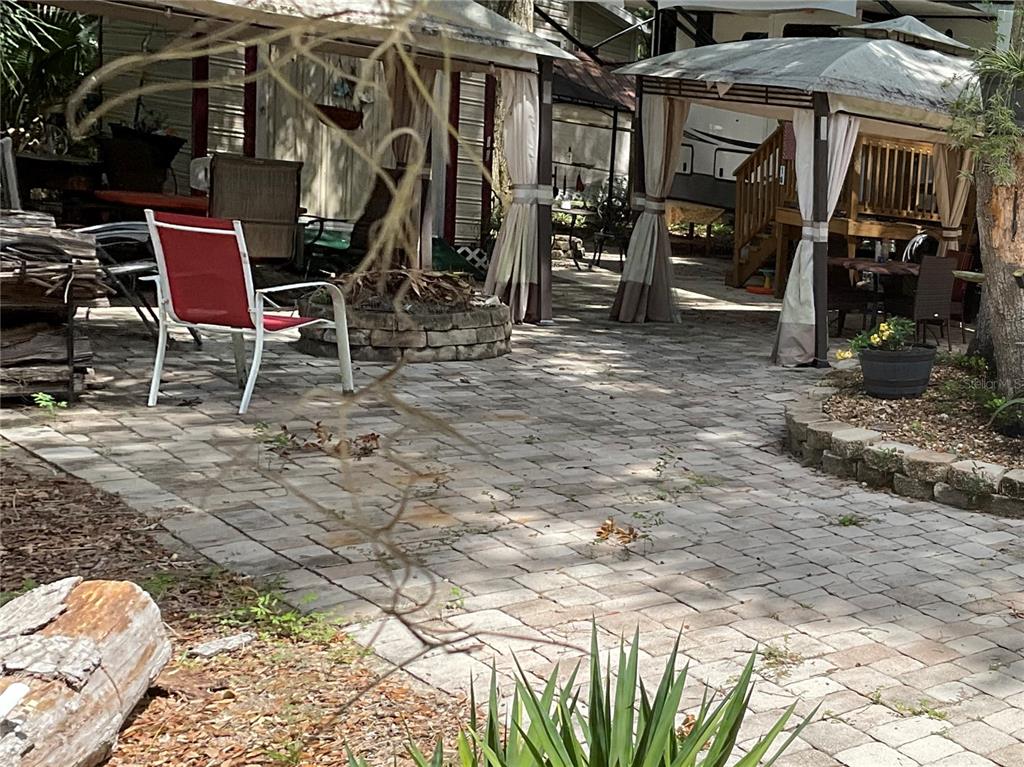 A paved patio area features a fire pit, two gazebos, and outdoor seating — 25191 NE 142ND PLACE, FORT MC COY, FL