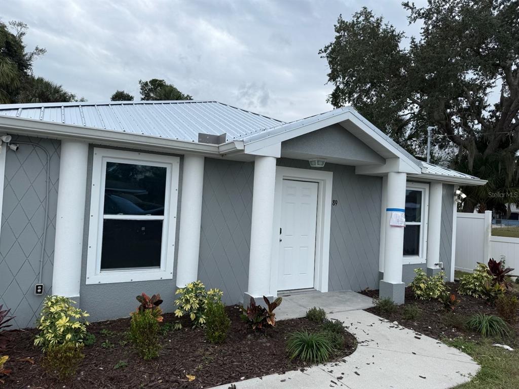 A gray house with a metal roof, white columns, and a white front door — 89 W IMOGENE STREET, ARCADIA, FL
