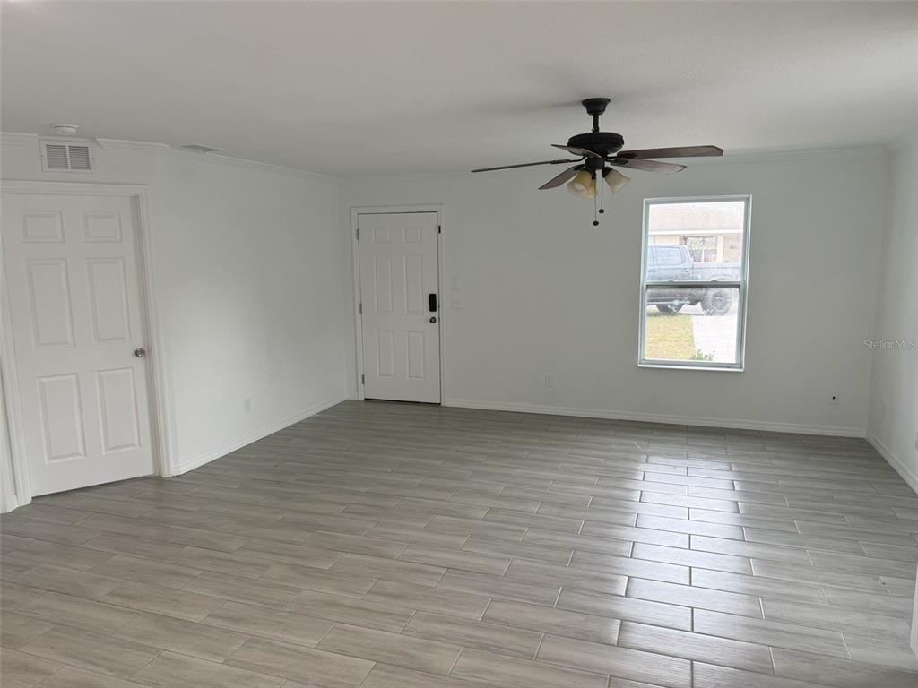 A living room features white walls, light gray wood-look tile flooring, and a ceiling fan — 89 W IMOGENE STREET, ARCADIA, FL