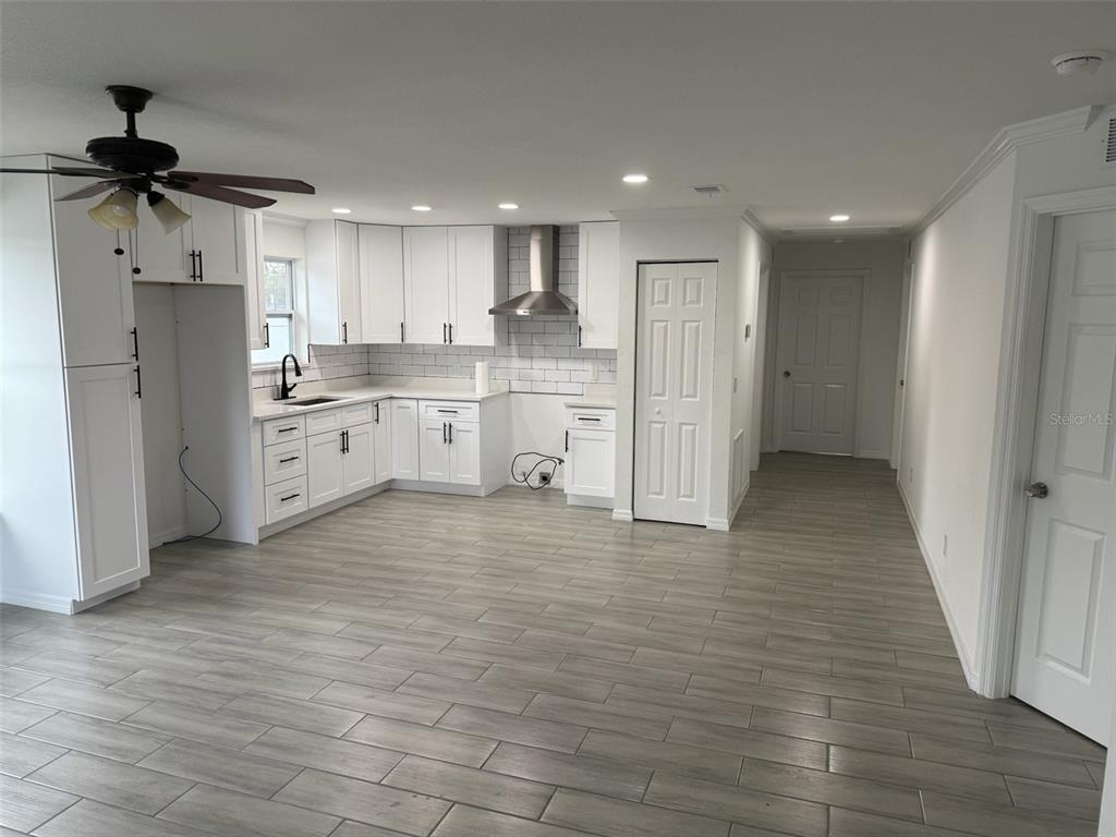 A modern kitchen features white cabinets, stainless steel range hood, and gray wood-look tile flooring — 89 W IMOGENE STREET, ARCADIA, FL