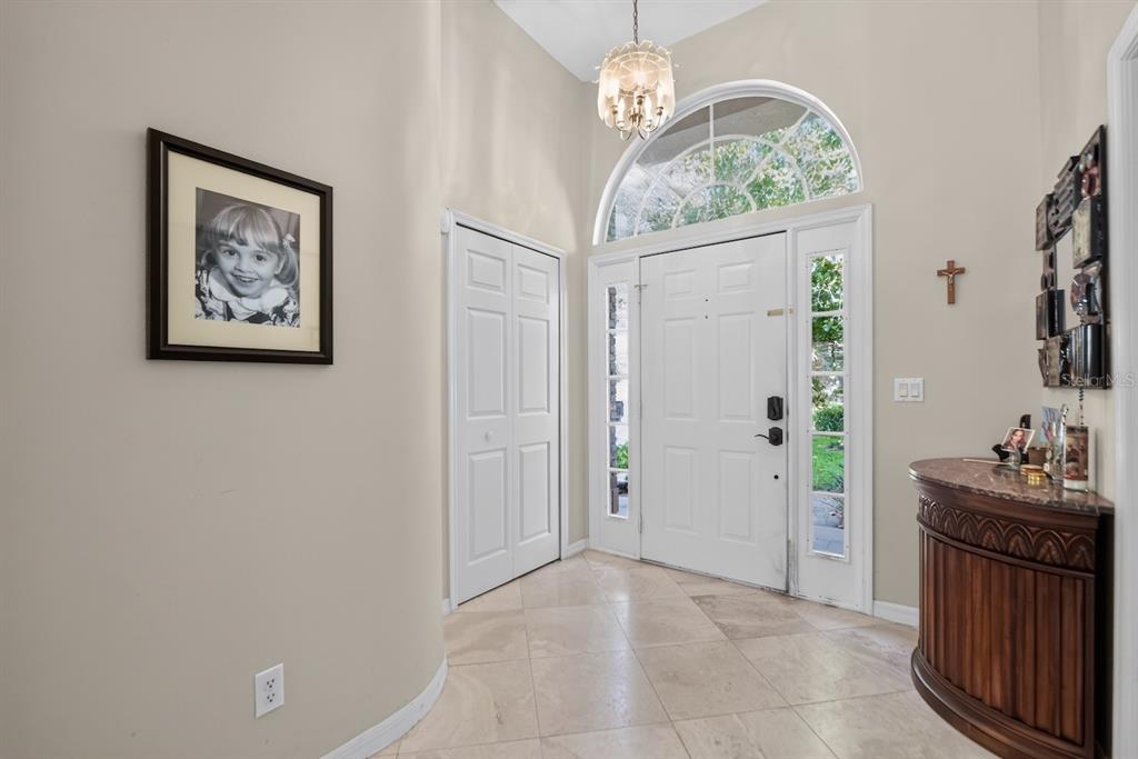A bright entryway features tile flooring, a white front door with sidelights, and a chandelier — 7691 BELVOIR DRIVE, ORLANDO, FL