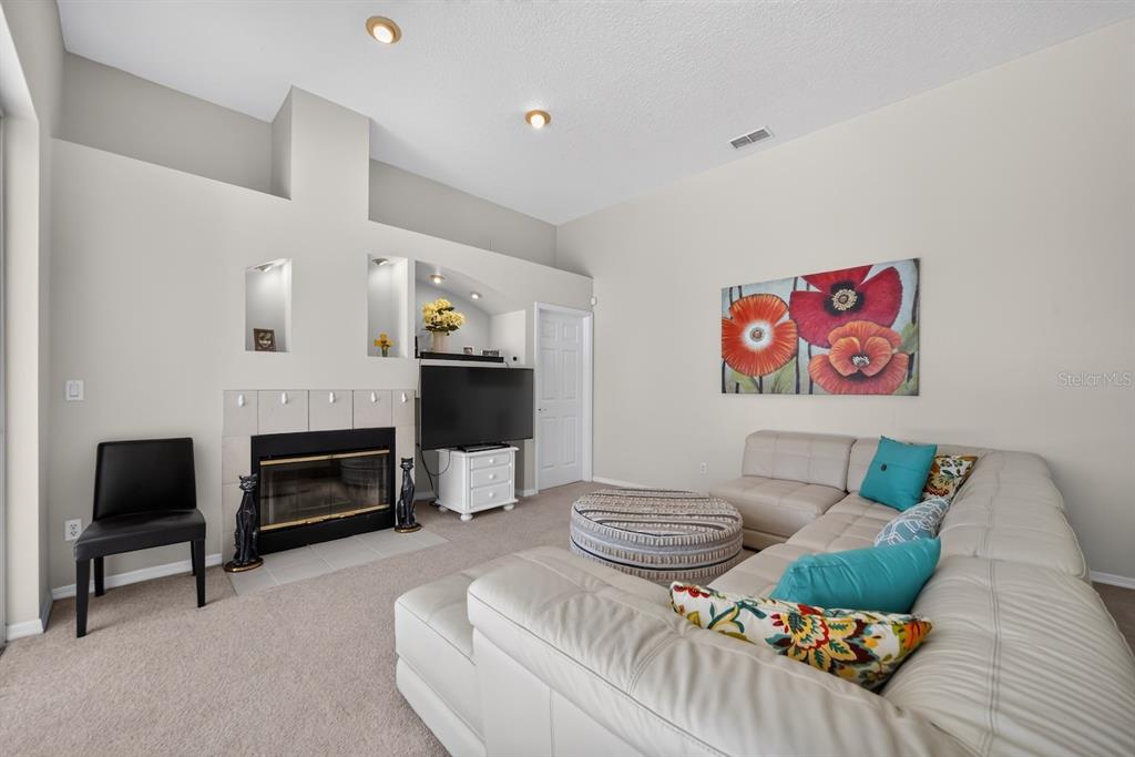 A living room features a fireplace, a television, a sectional sofa, and a wall painting — 7691 BELVOIR DRIVE, ORLANDO, FL