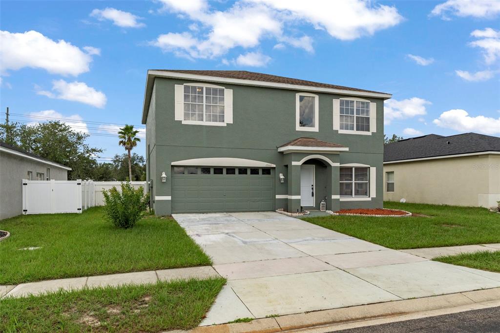 A two-story green house with a two-car garage and a white front door — 15160 DURANGO CIRCLE, BROOKSVILLE, FL