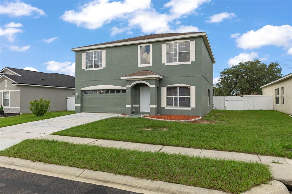 A two-story, sage green suburban house with a two-car garage and a front porch — 15160 DURANGO CIRCLE, BROOKSVILLE, FL