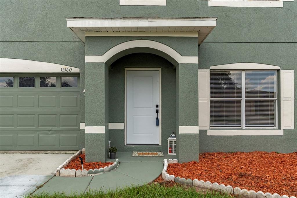The exterior of a green house features a white front door, arched entryway, and garage — 15160 DURANGO CIRCLE, BROOKSVILLE, FL