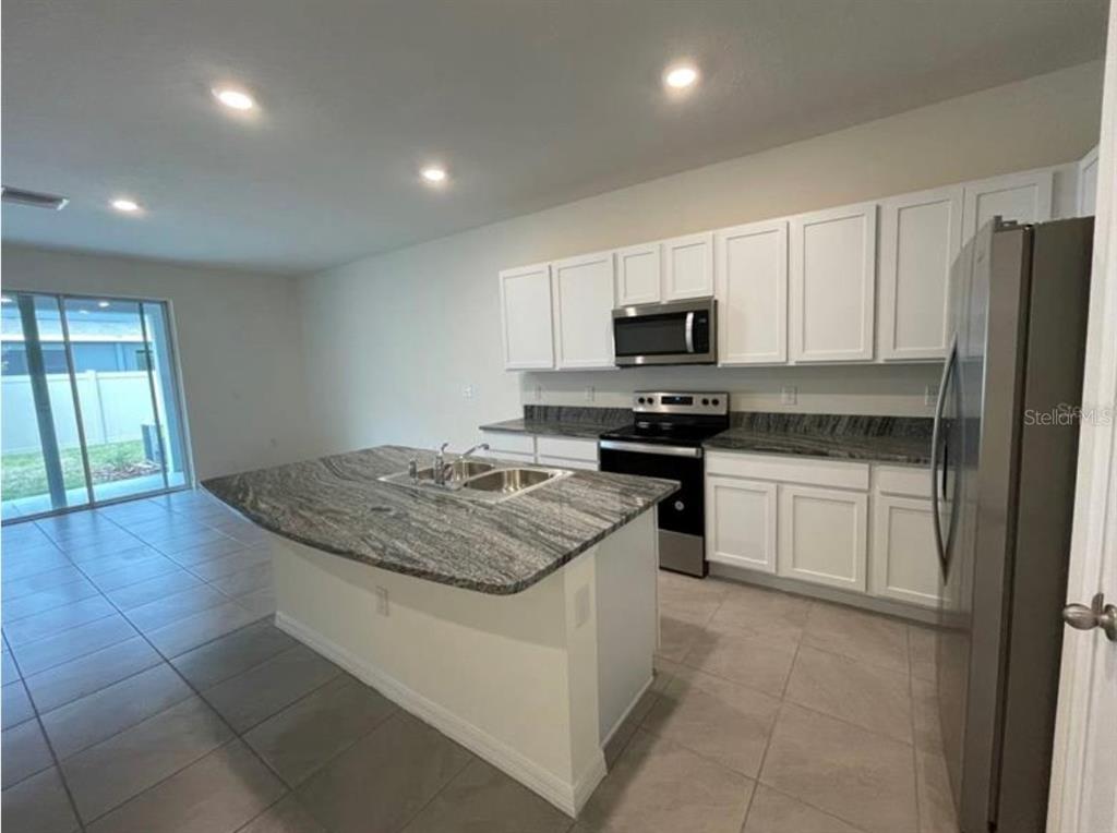 A kitchen with white cabinets, granite countertops, a center island, and stainless steel appliances — 32971 PEZ LANDING LANE, WESLEY CHAPEL, FL