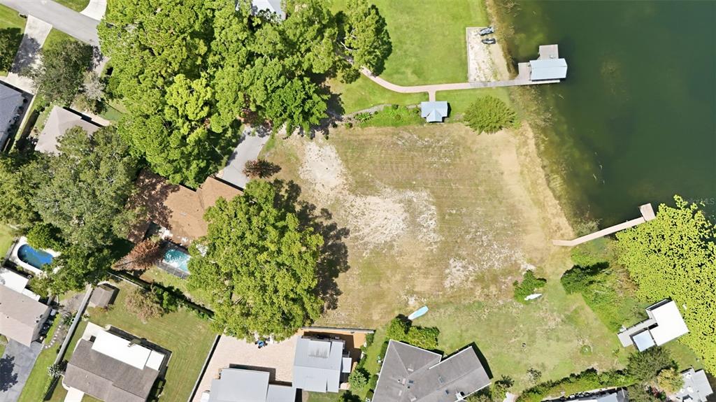 An aerial view shows a grassy waterfront lot with a dock at sunset — 1810 PINEWAY COURT, MOUNT DORA, FL