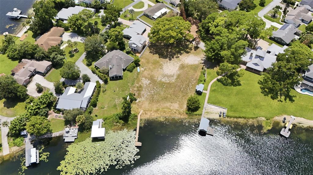 An aerial view shows a vacant waterfront lot with a private dock and surrounding houses — 1810 PINEWAY COURT, MOUNT DORA, FL