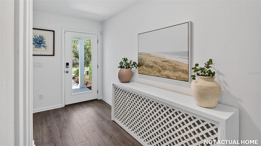 This entryway features a white radiator cover, a coastal landscape painting, and wood-look flooring — 25 DIVOT PLACE, BUNNELL, FL