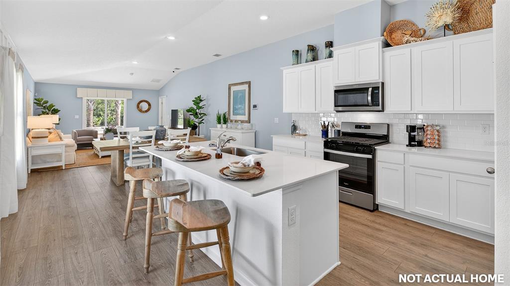 This is a rendering of an open-concept kitchen and living area with white cabinetry — 25 DIVOT PLACE, BUNNELL, FL