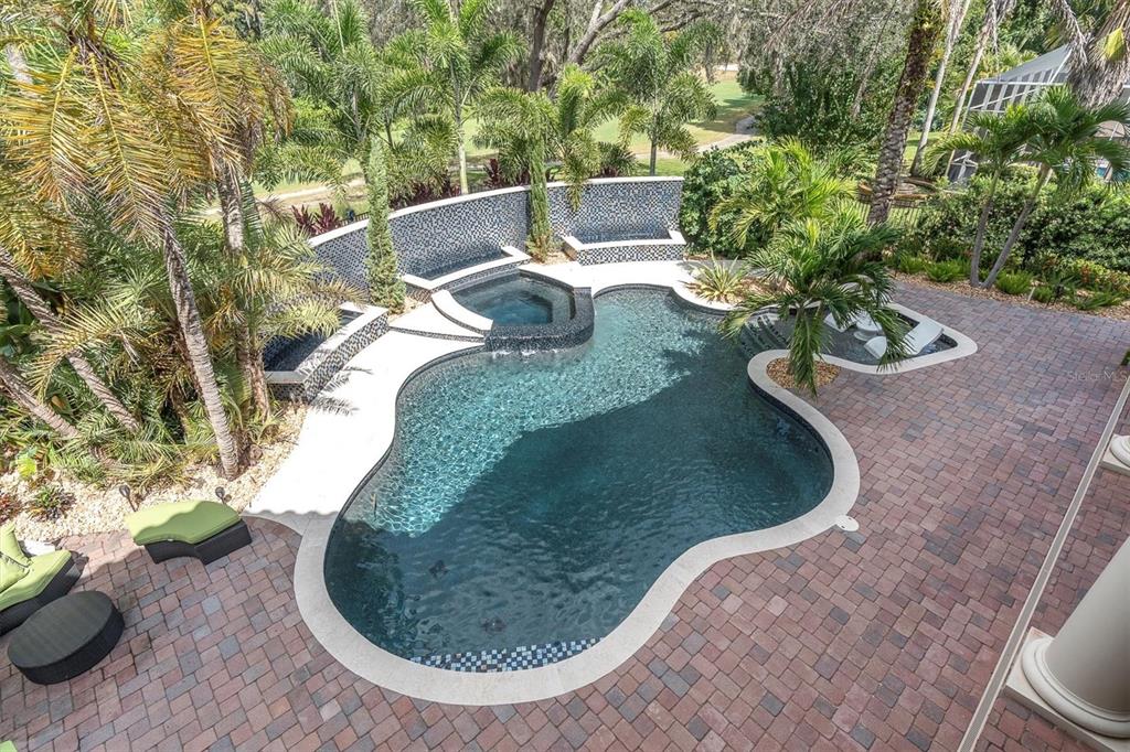 An aerial view of a freeform swimming pool with a spa and brick paver patio — 2861 ROEHAMPTON CLOSE, TARPON SPRINGS, FL