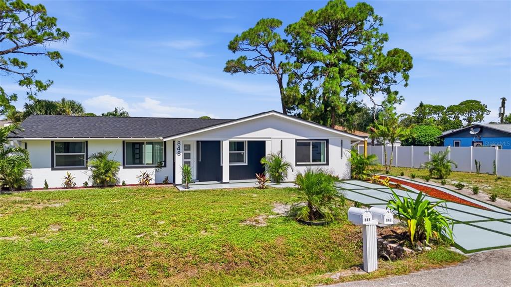 A single-story house with a white exterior, dark roof, and a paved driveway — 848 OLYMPIA ROAD, VENICE, FL