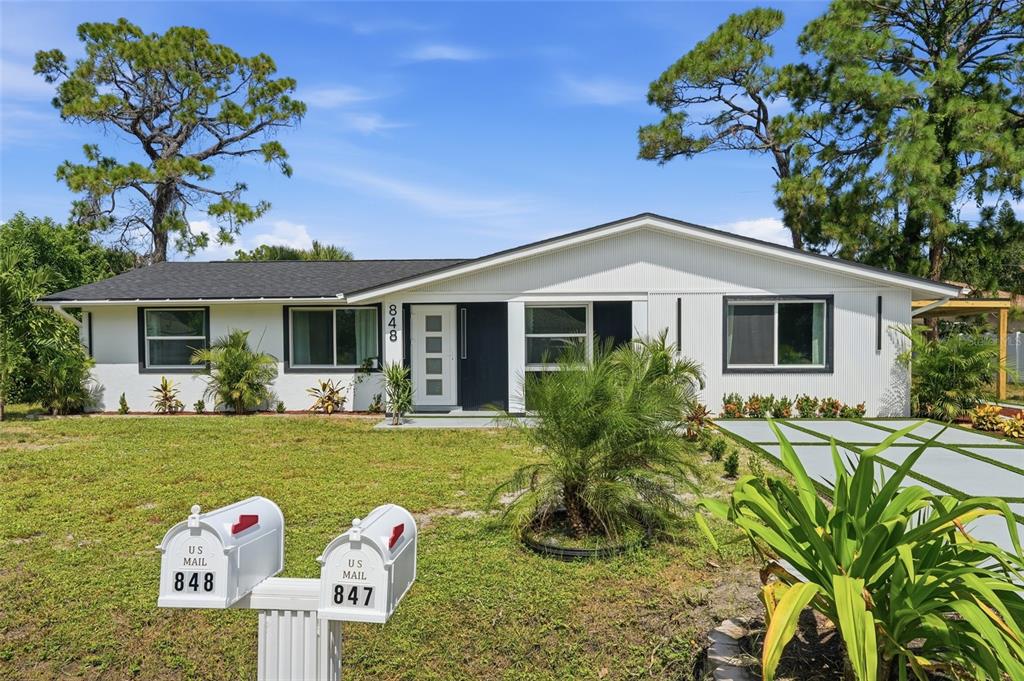 A single-story house with white corrugated siding, a dark roof, and two mailboxes in front — 848 OLYMPIA ROAD, VENICE, FL