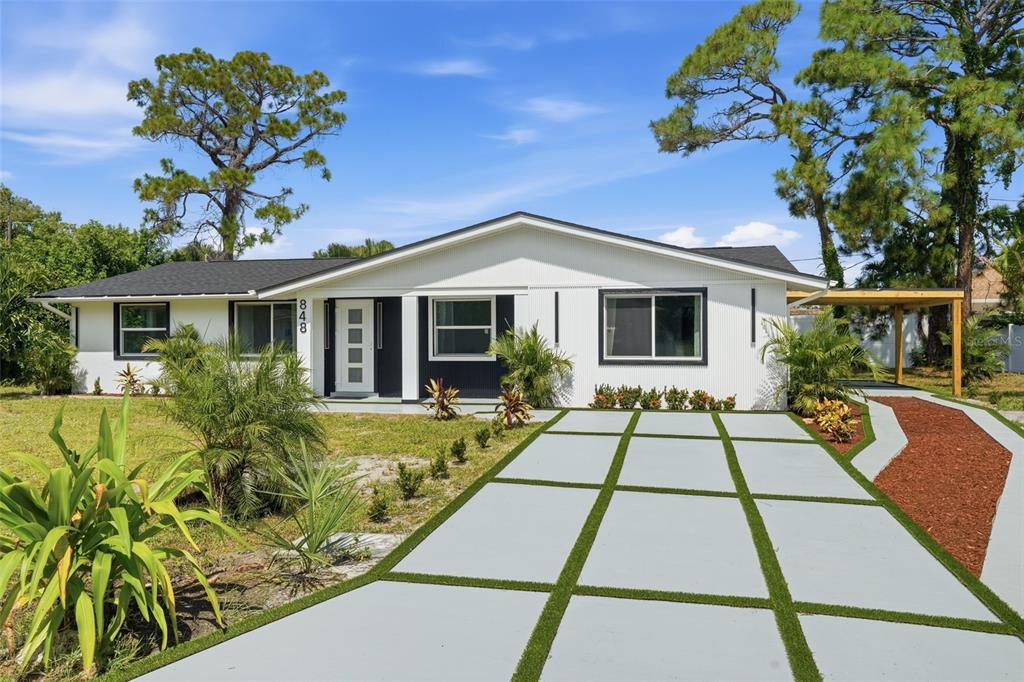 A white single-story house features a modern grid-pattern driveway and a covered side carport — 848 OLYMPIA ROAD, VENICE, FL