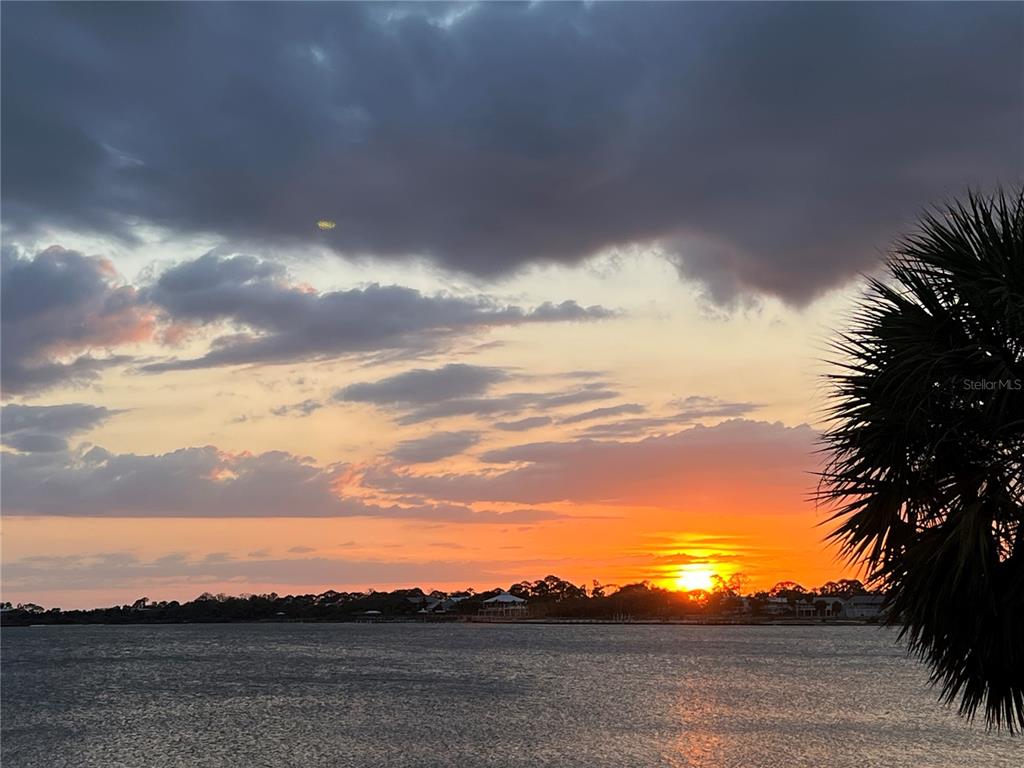 A sunset view over a body of water with a palm tree in the foreground — 850 3RD STREET UNIT 2, CEDAR KEY, FL