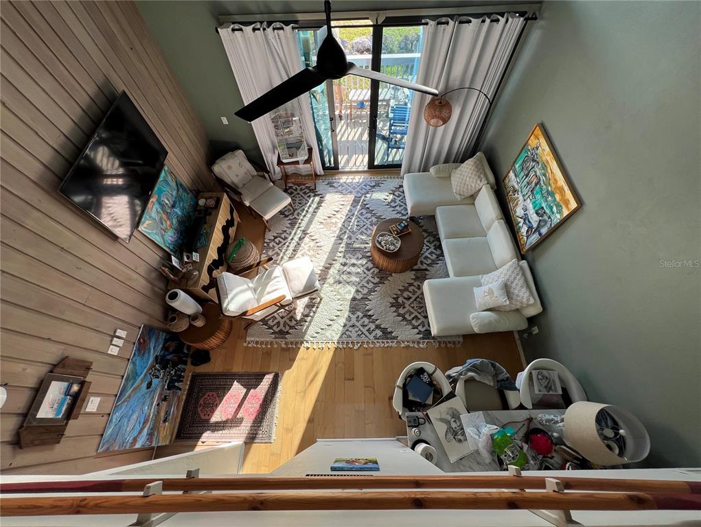 A high-angle view of a living room with a sectional sofa, armchairs, and wood paneling — 850 3RD STREET UNIT 2, CEDAR KEY, FL
