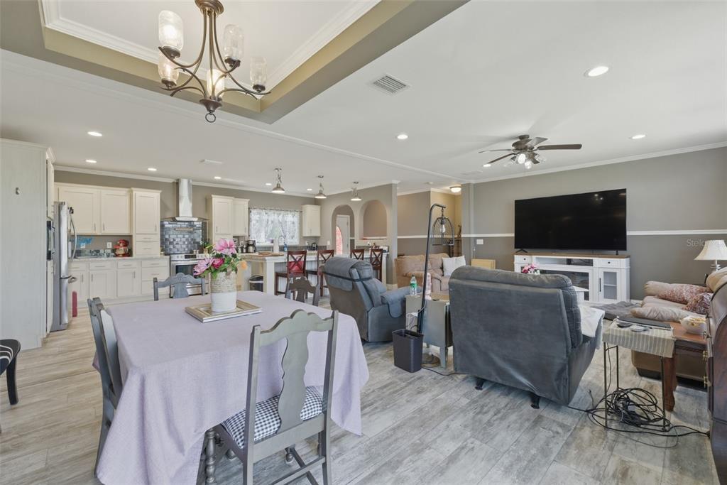 An open-concept living room and kitchen area features light wood-look flooring and neutral walls — 498 QUAIL HOLLOW BOULEVARD, CHIPLEY, FL