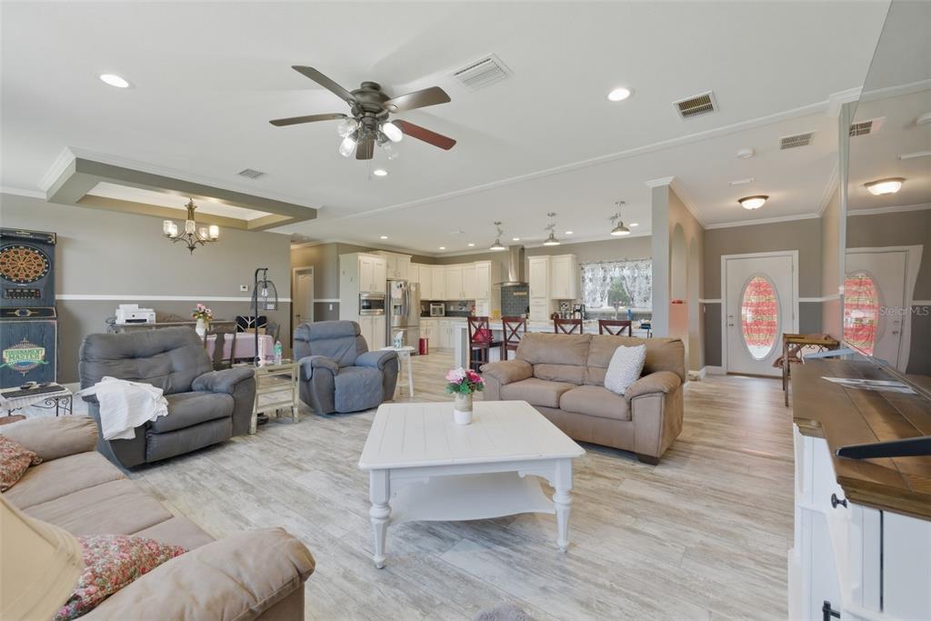 An open-concept living room and kitchen featuring light wood-look flooring and neutral wall colors — 498 QUAIL HOLLOW BOULEVARD, CHIPLEY, FL
