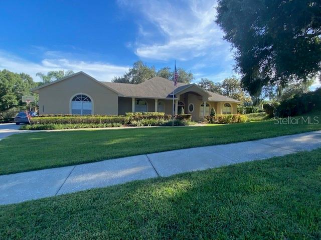A single-story house with a tan exterior, a gray roof, and a front lawn — 11812 OSPREY POINTE BOULEVARD, CLERMONT, FL