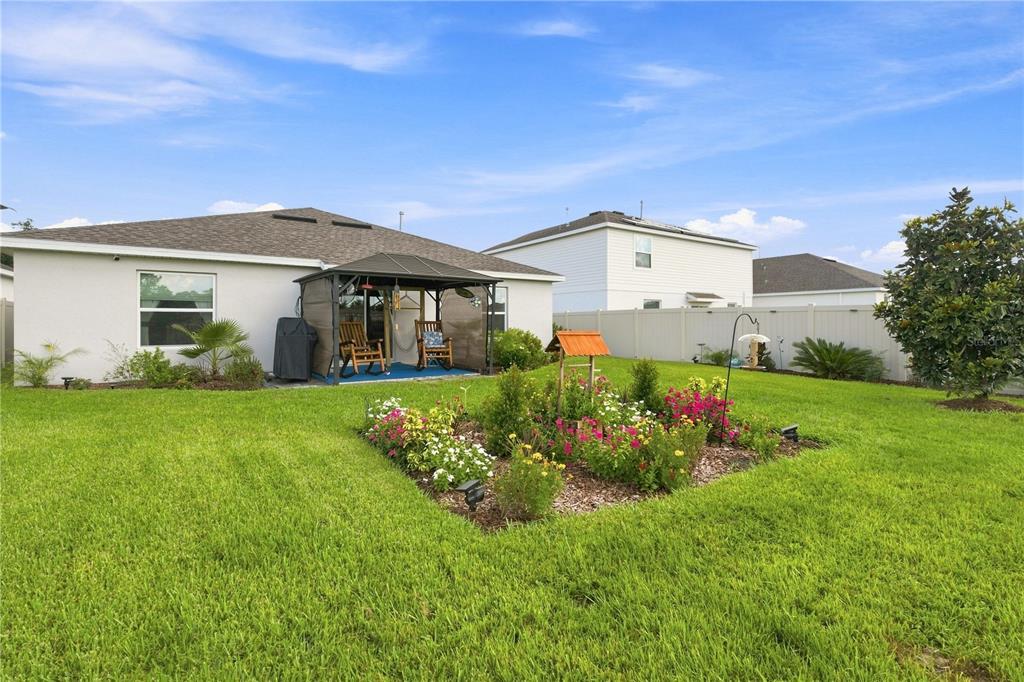 The backyard features a grassy lawn, a gazebo, and a white vinyl privacy fence — 33647 SKY BLOSSOM CIRCLE, LEESBURG, FL