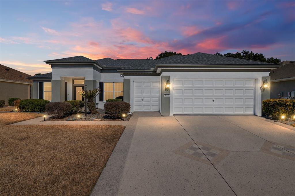 A single-story house with a white garage, gray trim, and a decorative concrete driveway — 9003 SE 118TH LANE, SUMMERFIELD, FL