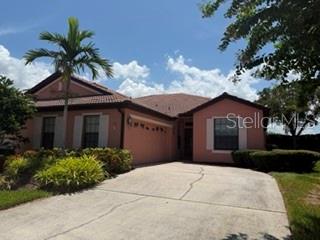 A single-story peach-colored house with a tile roof, a palm tree, and a concrete driveway — 147 SHELL FALLS DRIVE, APOLLO BEACH, FL