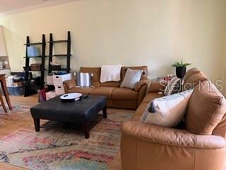 A living room features a brown leather sofa, a matching loveseat, and a black ottoman — 147 SHELL FALLS DRIVE, APOLLO BEACH, FL