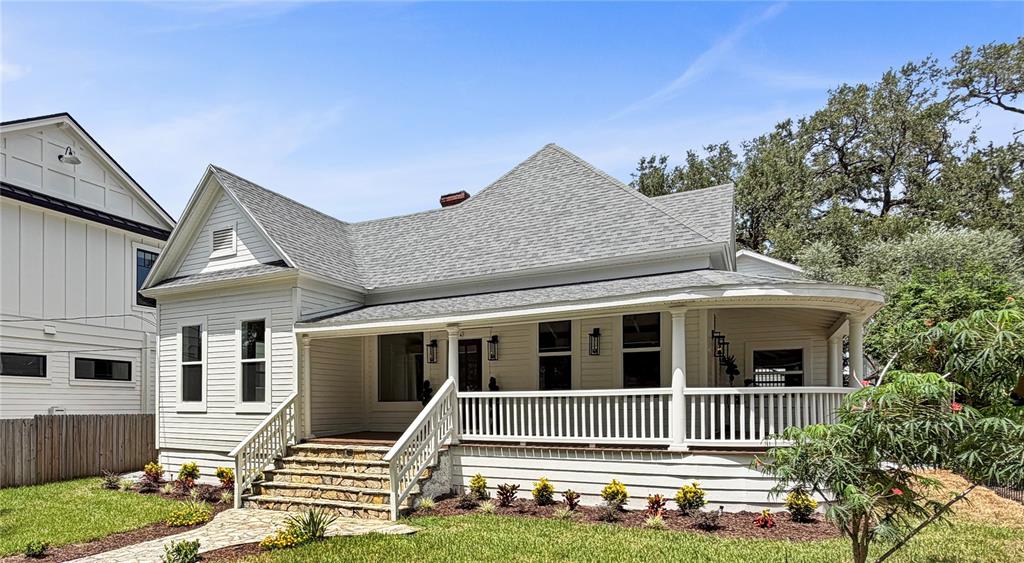 A covered front porch features white horizontal siding, a dark gray door, and two topiary plants — 317 W FRANCES AVENUE, TAMPA, FL