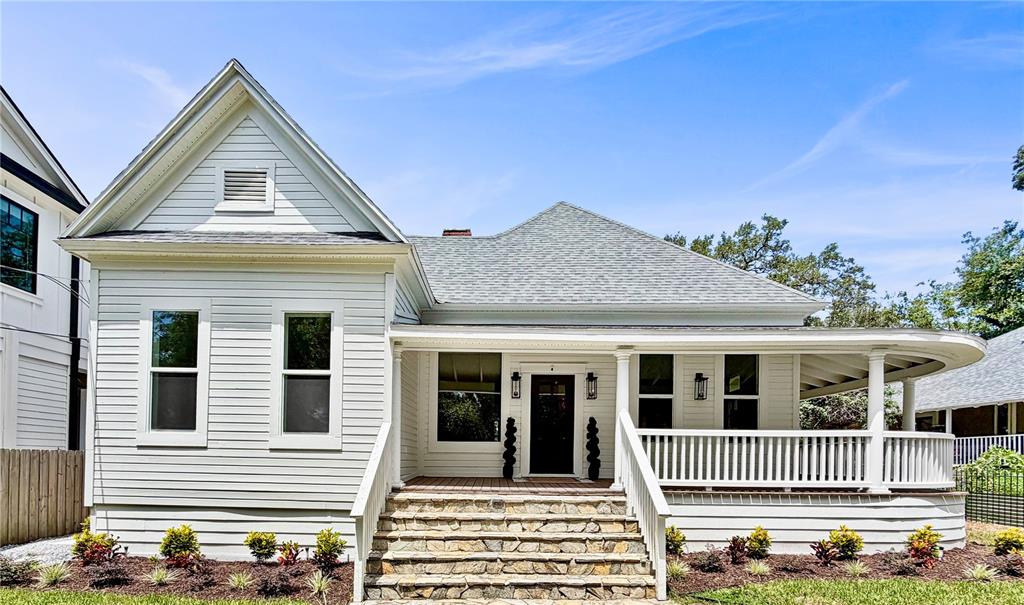A white-sided house features a covered wooden porch with black lanterns and potted plants — 317 W FRANCES AVENUE, TAMPA, FL