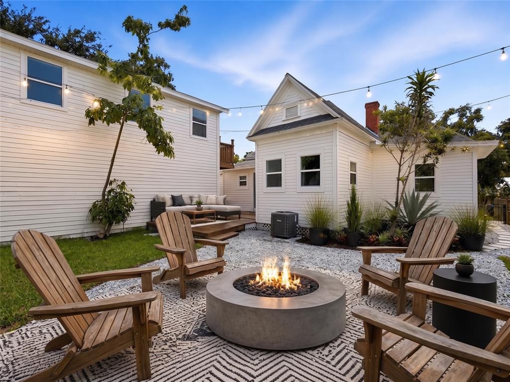 A backyard features a concrete fire pit, wooden Adirondack chairs, and a white house exterior — 317 W FRANCES AVENUE, TAMPA, FL