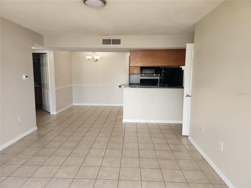 A tiled living area opens to a dining space and a kitchen with dark cabinets — 803 LAKE HAVEN SQUARE UNIT 101, BRANDON, FL