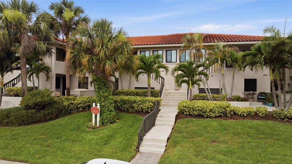 A two-story apartment building with a red tile roof, palm trees, and a concrete walkway — 1802 MARINER DRIVE E UNIT 25, TARPON SPRINGS, FL