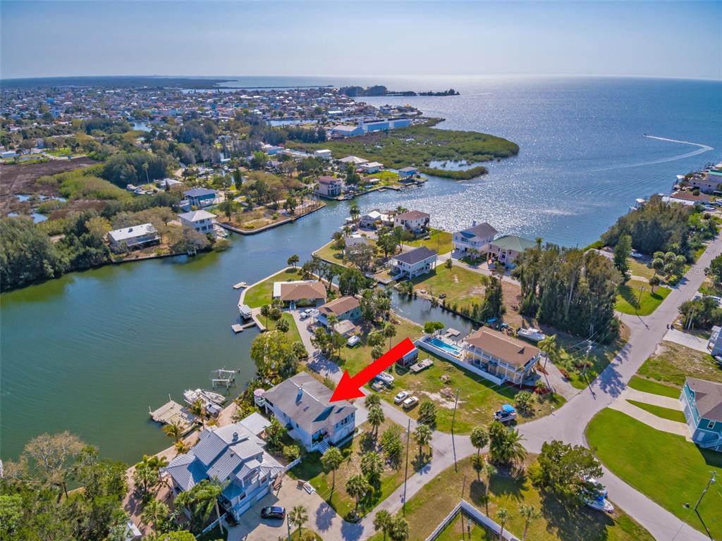 An aerial view shows a waterfront house with a red arrow pointing to its roof — 6810 SEAVIEW BOULEVARD, HUDSON, FL