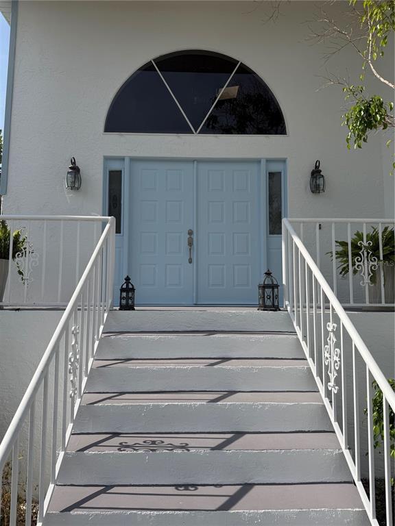 A set of concrete stairs leads up to light blue double doors under an arched window — 6810 SEAVIEW BOULEVARD, HUDSON, FL