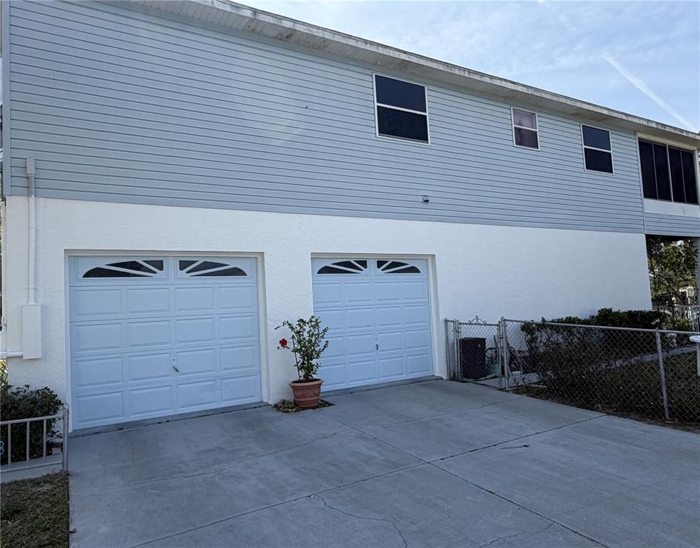A two-story house exterior features two white garage doors and light blue horizontal siding — 6810 SEAVIEW BOULEVARD, HUDSON, FL