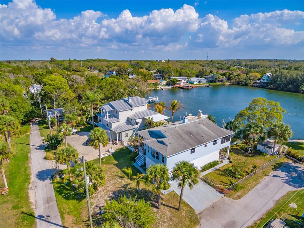 An aerial view shows two waterfront houses with palm trees and a boat dock — 6810 SEAVIEW BOULEVARD, HUDSON, FL