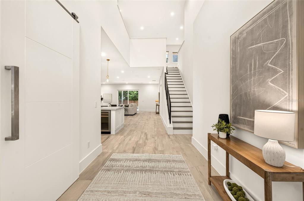 A bright entryway leads to a staircase and an open-concept kitchen with light wood flooring — 2343 VERSAILLES AVENUE, WINTER PARK, FL